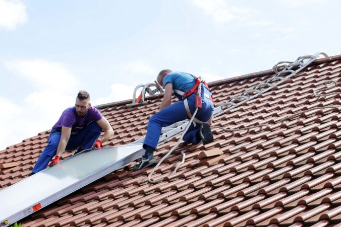 Zu sehen sind Installateure auf einem dach mit Sonnenkollektor. Die Solarthermie Förderung führt zu vermehrten Installationen.